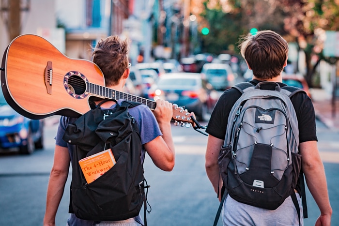 what is a hostel - two travelers walking with a guitar