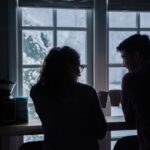 what to ask before you move in together - couple clinking mugs before a snowy scene
