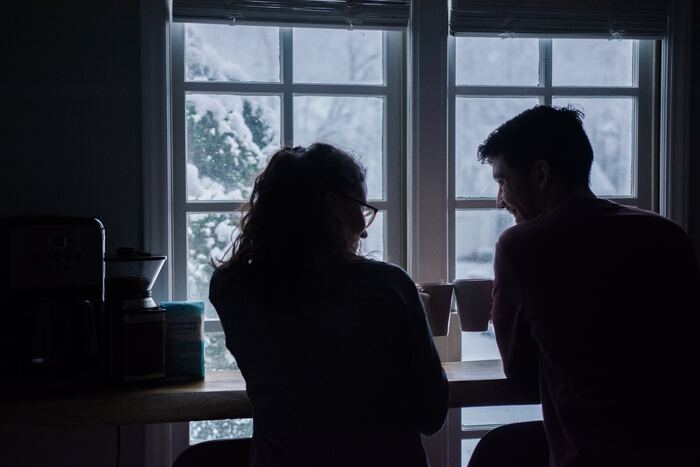 what to ask before you move in together - couple clinking mugs before a snowy scene