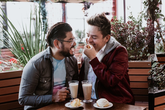 best LGBTQ dating apps - hispanic lgbt gay couple spending time together tasting bread and drinking coffee in a Latin american city